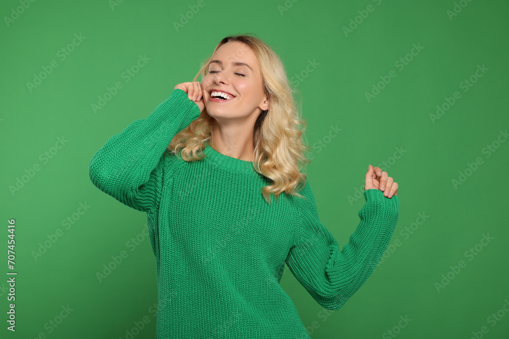 Happy woman in stylish warm sweater on green background Happy woman in stylish warm sweater on green background