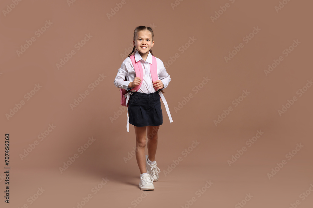 Happy schoolgirl with backpack on brown background Happy schoolgirl with backpack on brown background