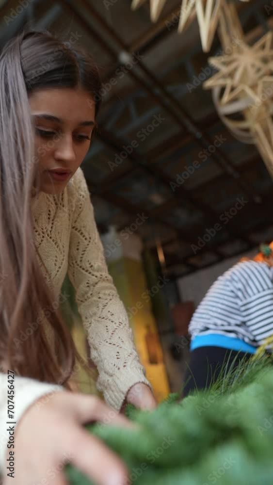 The finishing details on the Christmas wreath are completed at the flower shop counter.