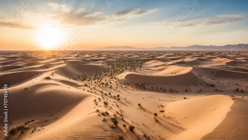 A vast desert with an oasis in the middle when the sun sets behind the dunes seen from a drone s perspective