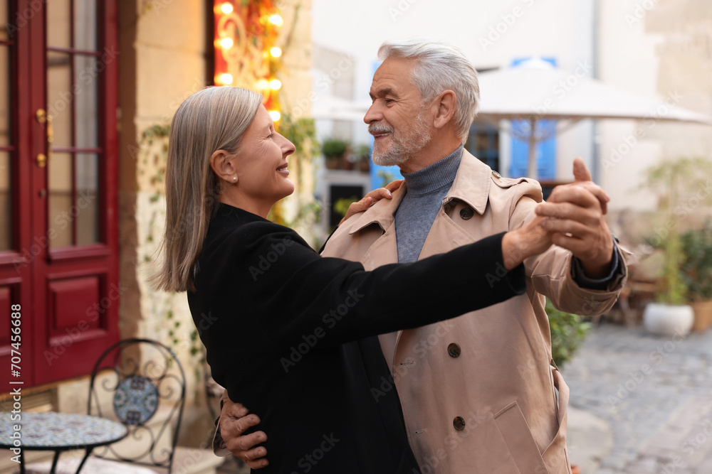 Affectionate senior couple dancing together on city street