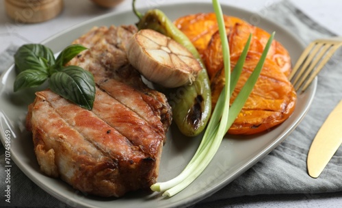 Delicious grilled meat and vegetables served on light grey table, closeup