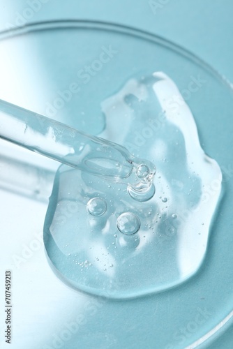 Pipette with cosmetic serum on light blue background, closeup