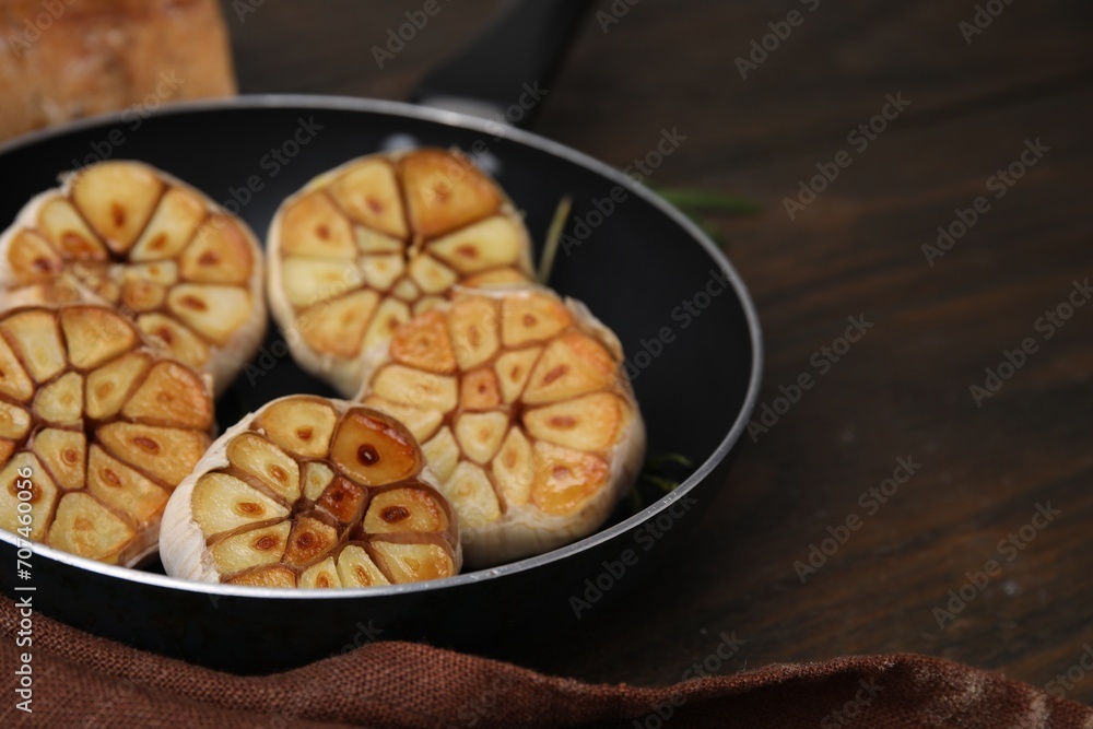 Frying pan with fried garlic on wooden table, closeup. Space for text Frying pan with fried garlic on wooden table, closeup. Space for text