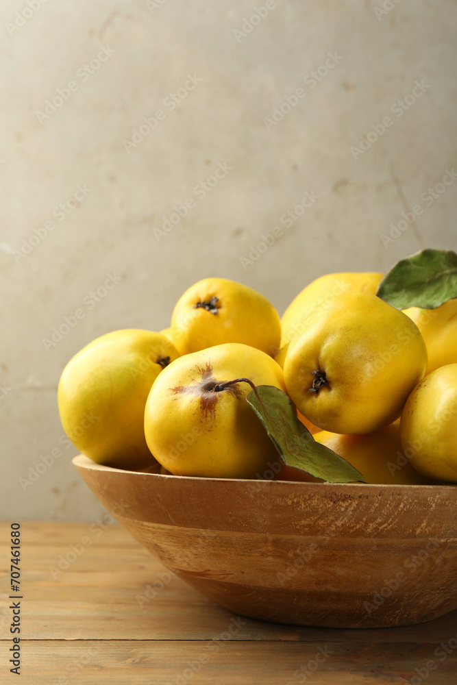 Φωτογραφία Tasty ripe quince fruits in bowl on wooden table, closeup