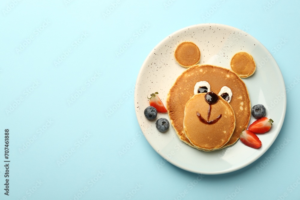 Creative serving for kids. Plate with cute bear made of pancakes and berries on light blue table, top view. Space for text - obrazy, fototapety, plakaty 