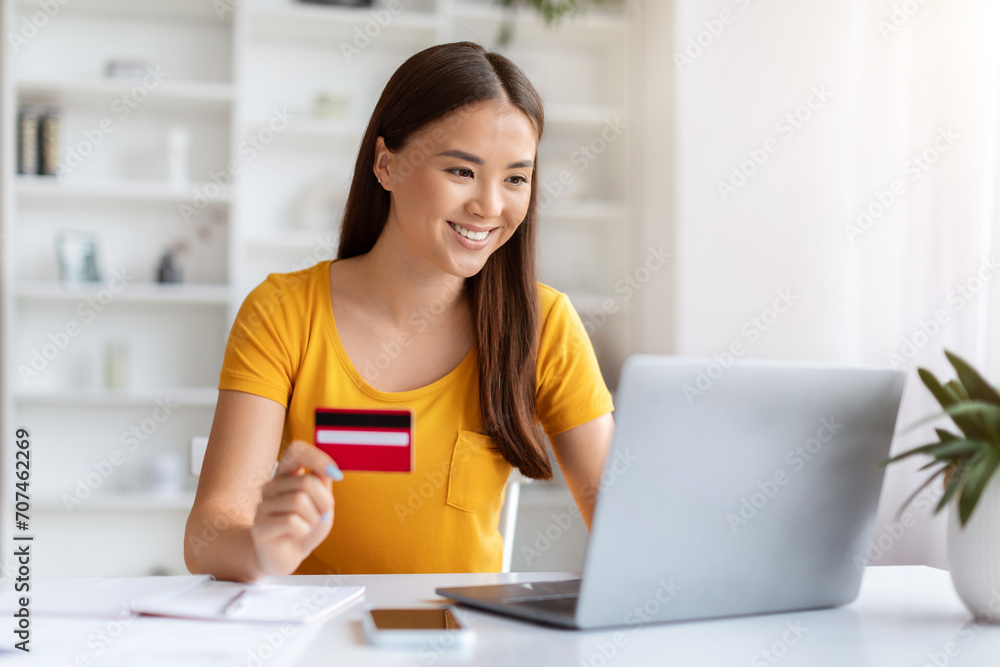 Smiling Asian Female Freelancer Using Laptop And Credit Card In Home Office Smiling Asian Female Freelancer Using Laptop And Credit Card In Home Office