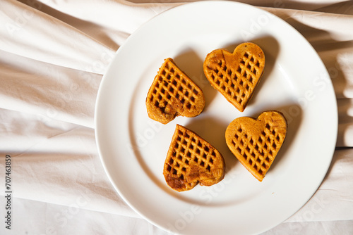 several waffles that looked delicious in the shape of a heart were served on a white plate