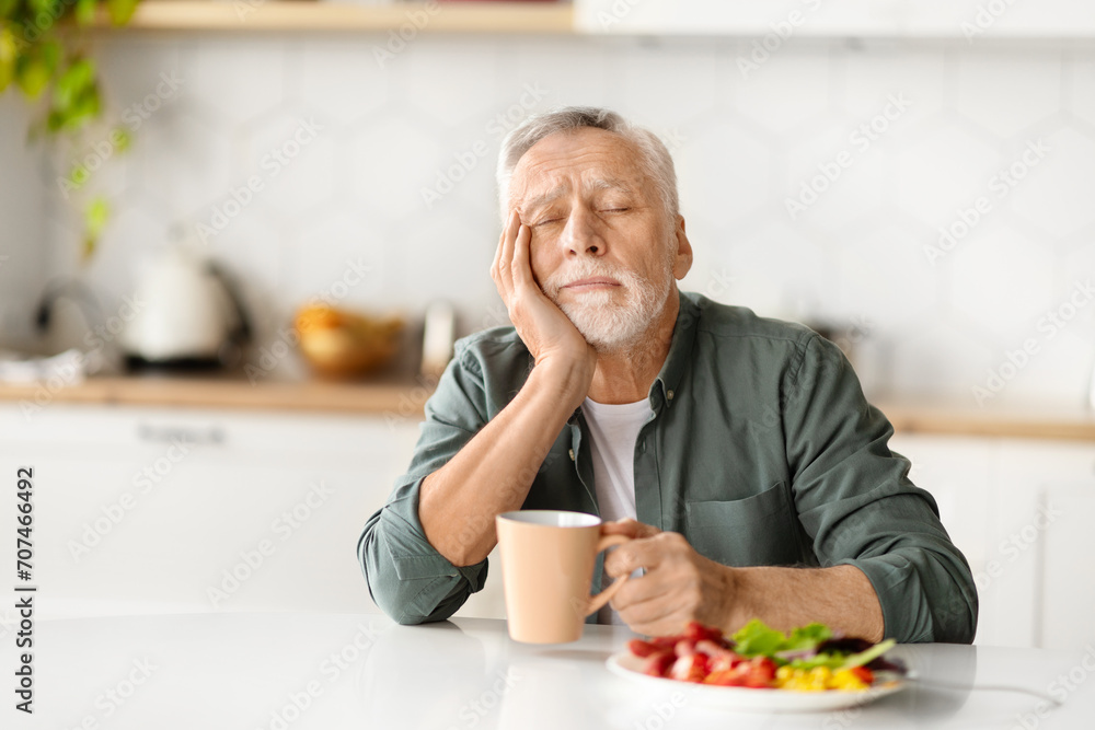 Tired elderly man resting his head on hand, falling asleep during breakfast Tired elderly man resting his head on hand, falling asleep during breakfast
