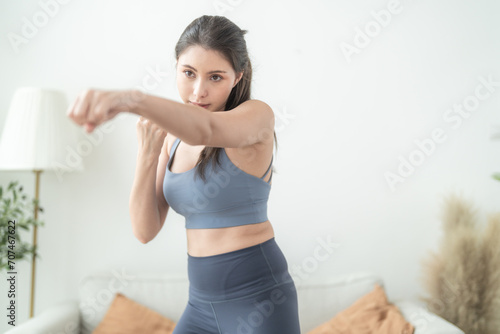 Attractive and strong woman stretching before fitness at indoor house. Healthy lifestyle. woman warm up by boxing in the air. Young female with slim body punching boxing footwork cardio exercise.