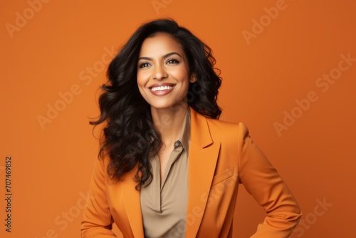 Portrait of happy smiling young businesswoman in orange suit, over orange background © Inigo