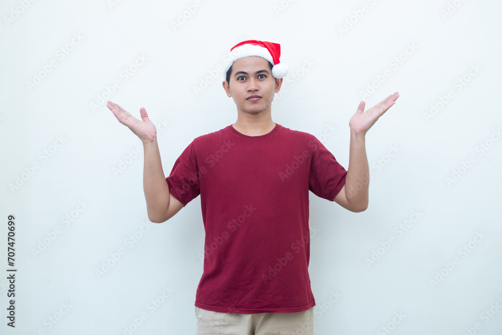Young Asian man wearing a Santa Claus hat smiling, shock and pointing to her side isolated by white background for visual communication Young Asian man wearing a Santa Claus hat smiling, shock and pointing to her side isolated by white background for visual communication
