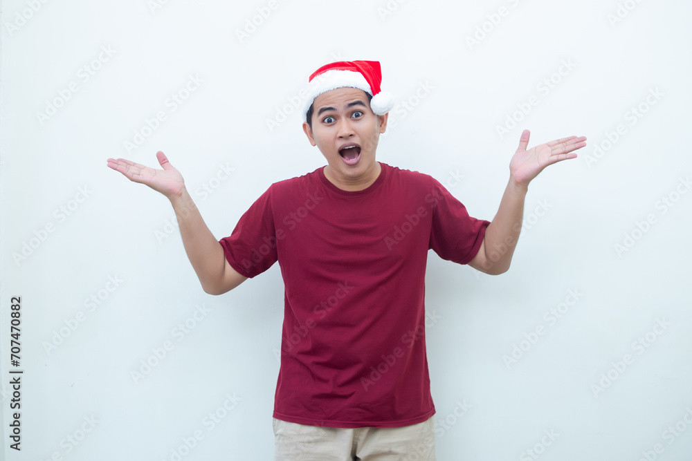 Young Asian man wearing a Santa Claus hat smiling, shock and pointing to her side isolated by white background for visual communication Young Asian man wearing a Santa Claus hat smiling, shock and pointing to her side isolated by white background for visual communication