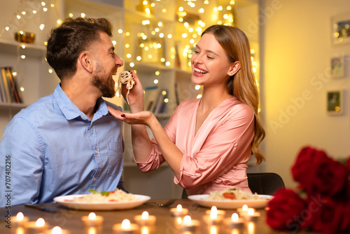 Joyful couple sharing pasta at a candlelit dinner