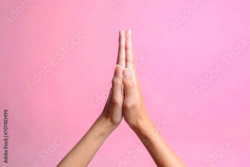 Female hands praying and begging God for forgiveness isolated on pink background.