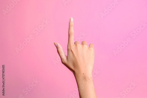 Woman hand pointing upwards isolated on pink background