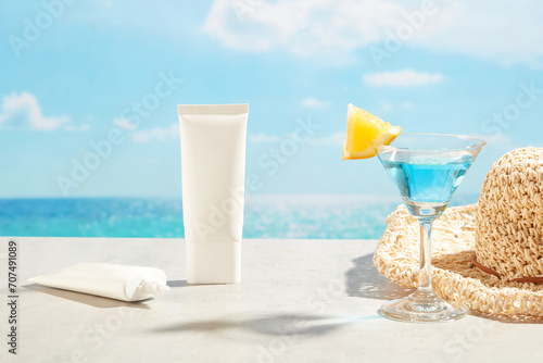 Blank label of two tubes of suntan or sun protection cream displayed with a hat and a cocktail glass. The concept of summer vacation by the water, skin care products. Summer time photo