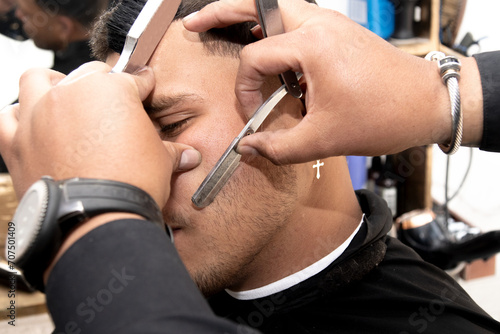 Close-up of a barber grooming the beard of a Latin man