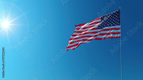 The American flag waves proudly under a bright sun, embodying freedom and patriotism in the clear blue sky. National symbol of pride and unity.