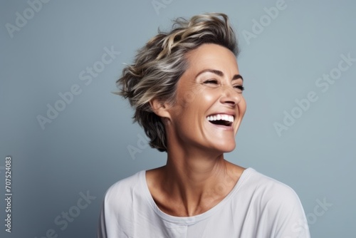 Portrait of a happy young woman laughing and looking up against grey background
