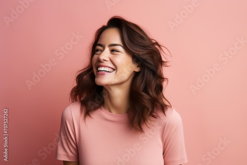 Portrait of beautiful young woman laughing and looking at camera over pink background