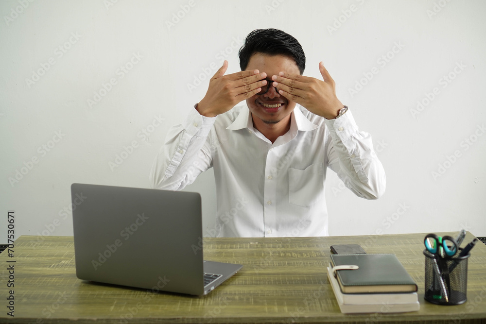 young asian businessman in a workplace covering eyes by hands wearing white shirt isolated young asian businessman in a workplace covering eyes by hands wearing white shirt isolated