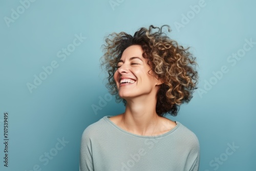 Portrait of a smiling young woman with curly hair on blue background