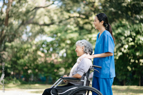 Elderly asian senior woman on wheelchair with Asian careful caregiver and encourage patient, walking in garden. with care from a caregiver and senior health insurance... © Nuttapong punna