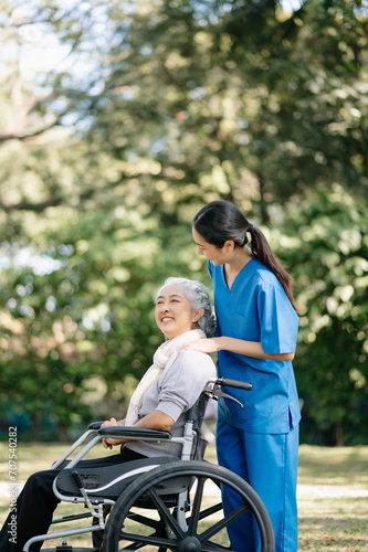 Elderly asian senior woman on wheelchair with Asian careful caregiver and encourage patient, walking in garden. with care from a caregiver and senior health insurance... © Nuttapong punna