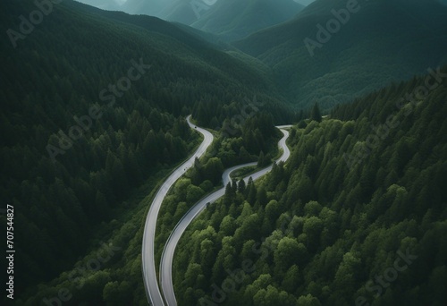 Aerial top view mountaint road in dark green forest