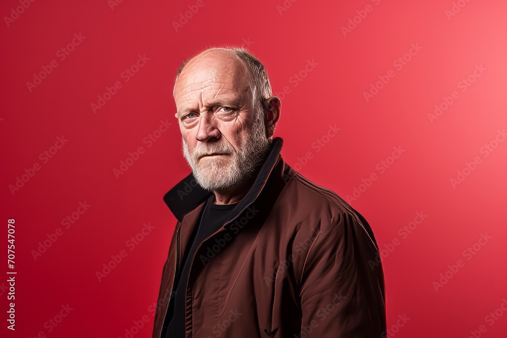 Portrait of a senior man on a red background. Studio shot.