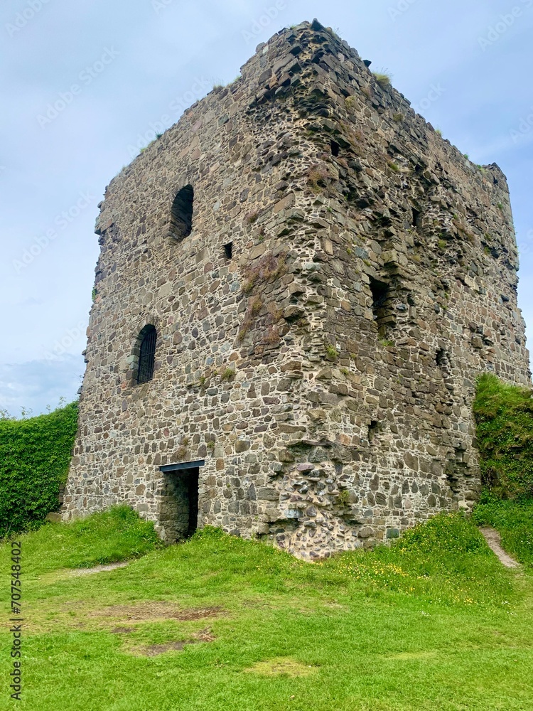 Stone tower in Scotland, abandoned and surrounded by green grass Stone tower in Scotland, abandoned and surrounded by green grass