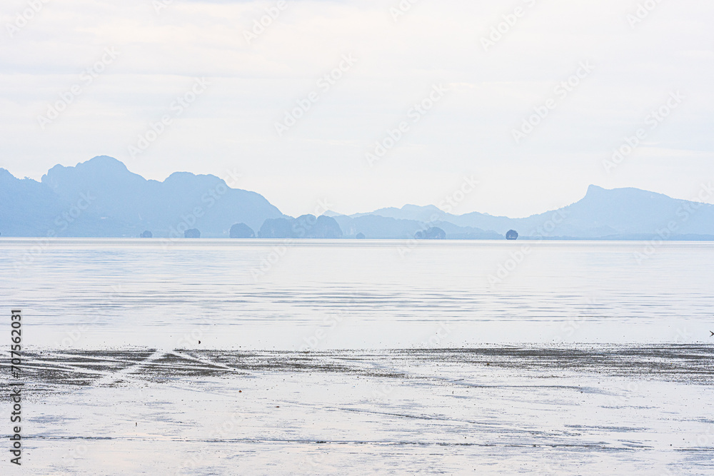 The distant mountains are complex, many with mangrove forests. There is a sea in front and a faint mist.
