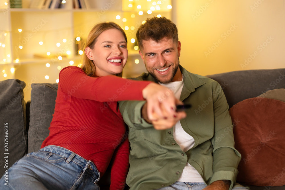 Obraz premium Cheerful couple with a remote control watching TV at home