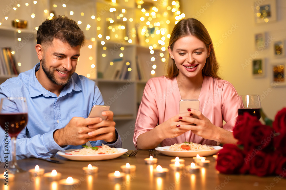 Couple at dinner, distracted by their smartphones Couple at dinner, distracted by their smartphones