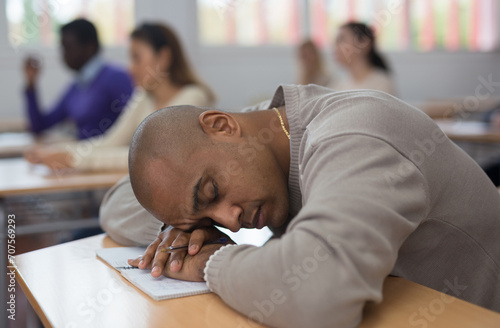 Portrait of tired hispanic man sleeping during lecture at adult education class.. photo