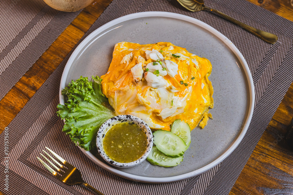 Omelet, fried beaten eggs on a white plate. Placed on a wooden table ready to eat. Omelet, fried beaten eggs on a white plate. Placed on a wooden table ready to eat.