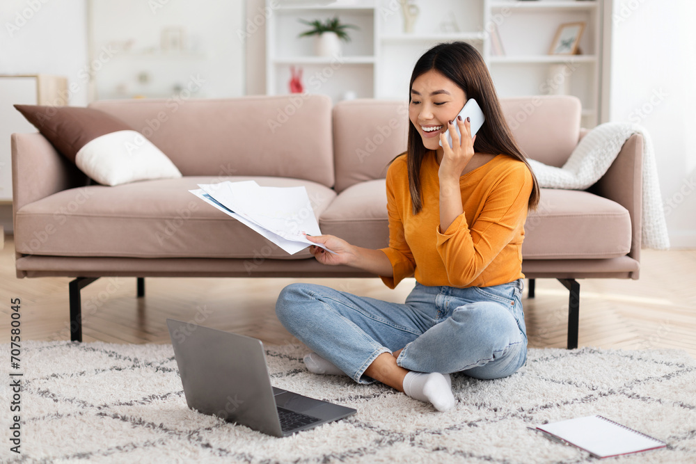 Asian woman freelancer working from home, talking on cell phone Asian woman freelancer working from home, talking on cell phone