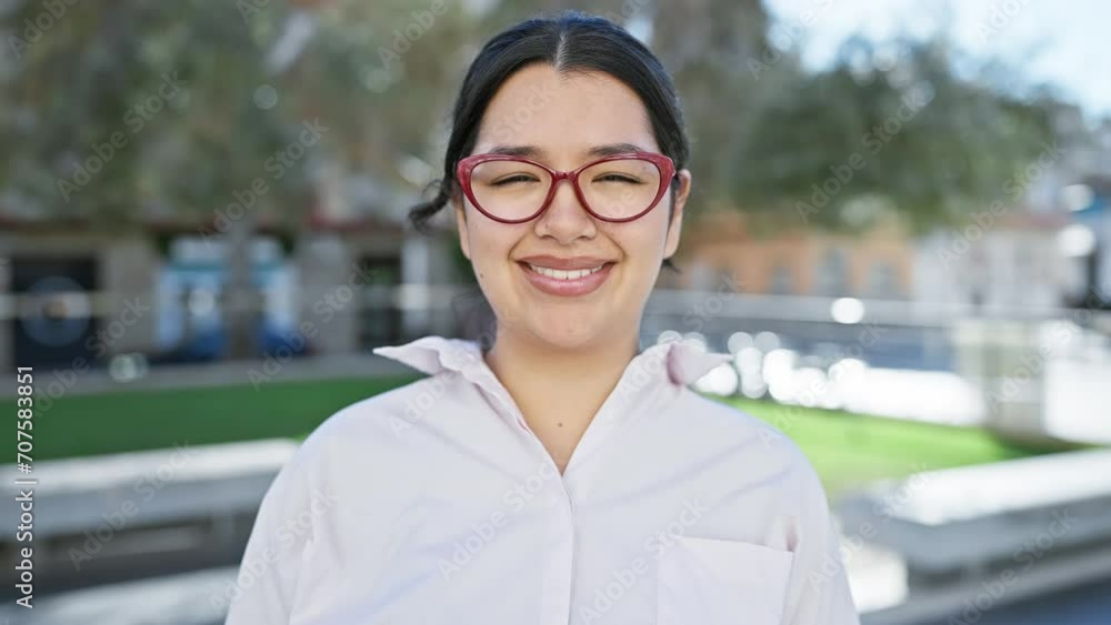 Smiling young hispanic woman wearing glasses in an urban city environment. Smiling young hispanic woman wearing glasses in an urban city environment.