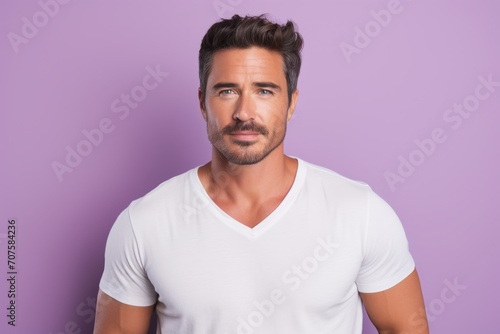 Portrait of handsome young man in white t-shirt on violet background