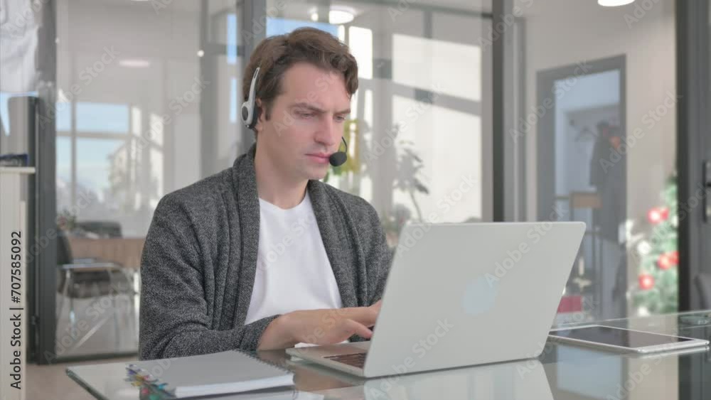 Young Man with Headset in Call Center Working on Laptop Young Man with Headset in Call Center Working on Laptop