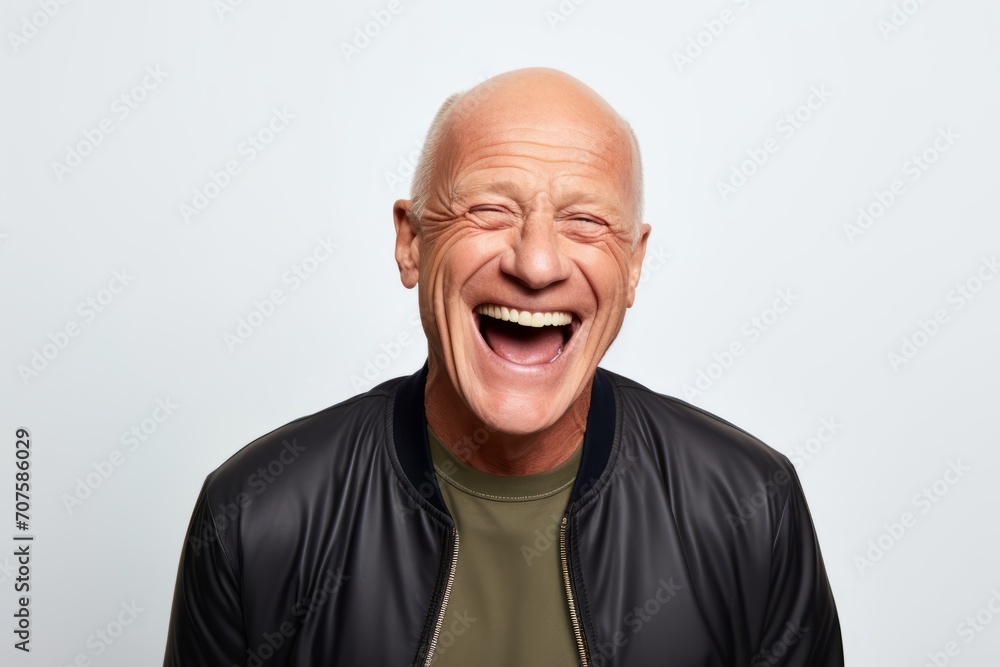 Portrait of a happy senior man laughing while standing against grey background Portrait of a happy senior man laughing while standing against grey background