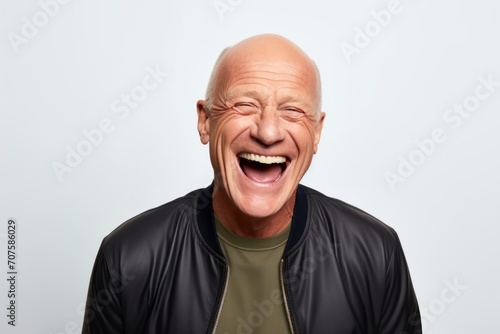 Portrait of a happy senior man laughing while standing against grey background