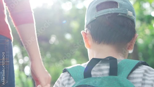 Asian Child boy and mother holding hands and walk in public park. Mom and son going to a preschool. Back to school.