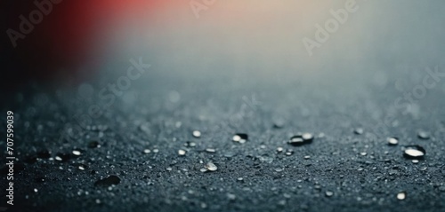  drops of water on a black surface with a red light in the backgroup of the image in the background.