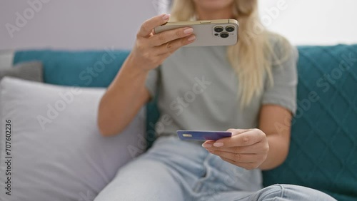 Blonde woman takes a photo of her credit card indoors on her smartphone photo