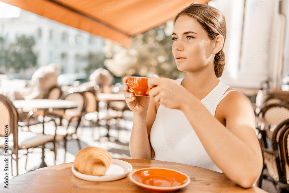 Portrait of happy woman sitting in a cafe outdoor drinking coffee. Woman while relaxing in cafe at table on street, dressed in a white T-shirt and jeans Portrait of happy woman sitting in a cafe outdoor drinking coffee. Woman while relaxing in cafe at table on street, dressed in a white T-shirt and jeans