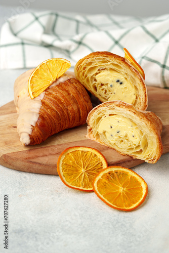 Glazed croissant with dried orange on wooden board