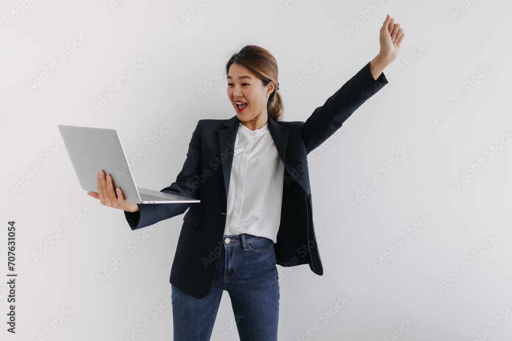 Asian Thai woman wear navy suit, spreading arms raising up and holding laptop with happy face, successful work, standing isolated over white background wall.