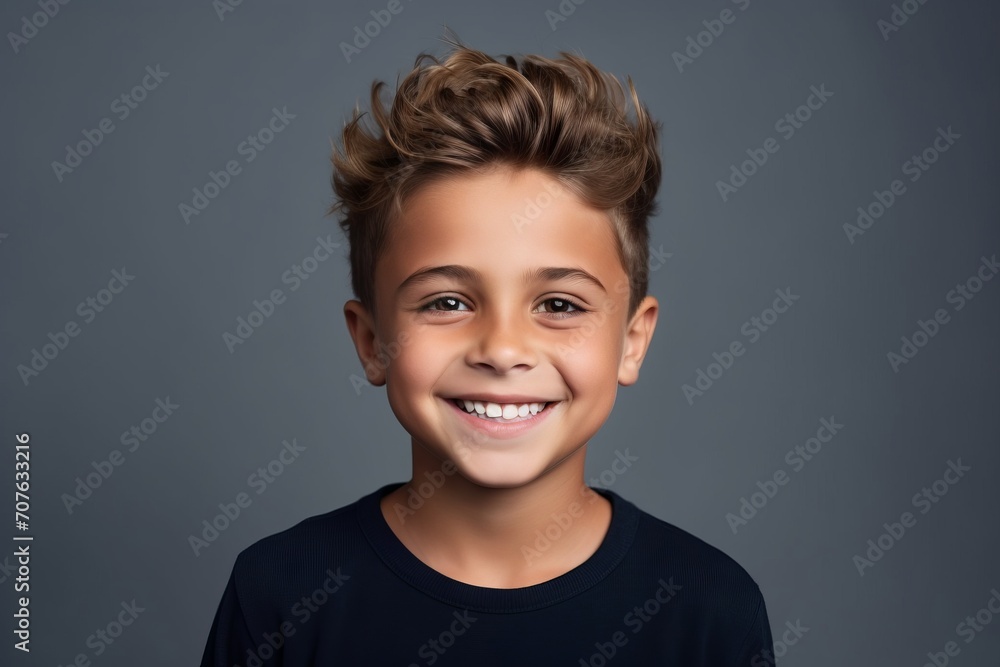 Portrait of a cute little boy smiling at camera against grey background Portrait of a cute little boy smiling at camera against grey background